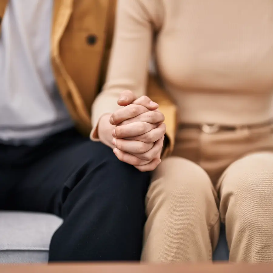 Terapia di coppia Torino: una coppia seduta sul divano con le mani intrecciate